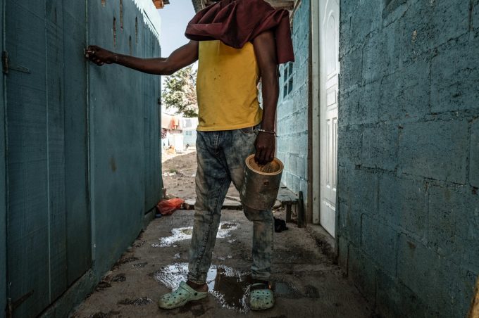 Dorsen, 22 anni, con in mano il secchio del mangime, si prepara a dare da mangiare alle sue galline. Batey Lichi Lichima, provincia de La Romana -  Repubblica Dominicana