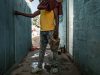 Dorsen, 22 anni, con in mano il secchio del mangime, si prepara a dare da mangiare alle sue galline. Batey Lichi Lichima, provincia de La Romana -  Repubblica Dominicana